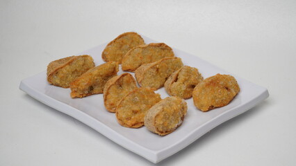 A plate of fried tahu walik is placed on a white base and background (isolated white).