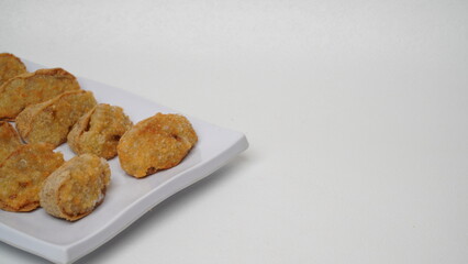 A plate of fried tahu walik is placed on a white base and background (isolated white).