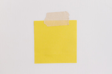 Blank yellow sticky notes with tape on a white background