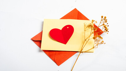 romantic Valentine&rsquo;s Day composition featuring a red envelope, a beige greeting card, and a red heart-shaped paper cutout, set against a white background, symbolizing love, affection
