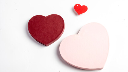 Three heart-shaped objects in different sizes and colors, including red, pink, and burgundy, placed on a white background, symbolizing love, romance, and affection for Valentine's Day