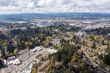 Obraz premium Aerial drone view of Southwest Portland, Oregon, featuring residential neighborhoods, tree-lined streets, rolling hills, and urban landscape with the downtown skyline visible in the distance
