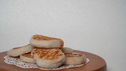 Wingko babat is served using a brown container made of wood and placed on a white background (isolated white).