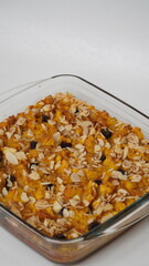 Whole pumpkin bread pudding topped with raisins and sliced ​​almonds served in a glass baking dish placed on a white background (isolated white).