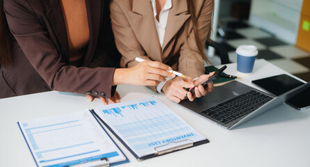 Business hand using laptop and tablet with social network diagram and two colleagues discussing data