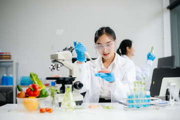 Fototapeta premium Two Asian scientists in a lab conducting food research using a microscope and lab equipment, showcasing innovation in food science