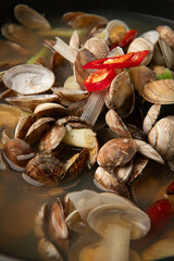 Cooked clams with chili pepper in pot, closeup. Seafood soup