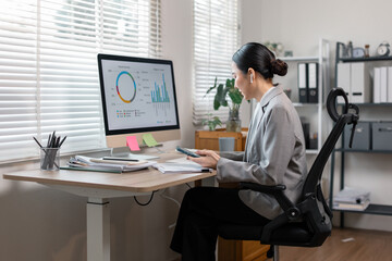Asian business finance market analyst holdind phone working at office .Business woman analyze...
