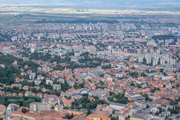 Naklejka premium Aerial view of Brasov surrounded by the Carpathian mountains dotted with ski resorts including the ever popular Boiana Brasov. Romania, the Balkans, Eastern Europe
