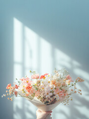 花束を持つ、フラワーアレンジメント。影のある部屋を背景