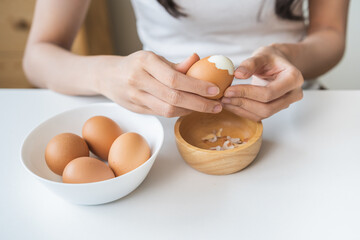 Protein in food, keto diet asian young woman hand peeling, shelling chicken boiled egg, prepares...