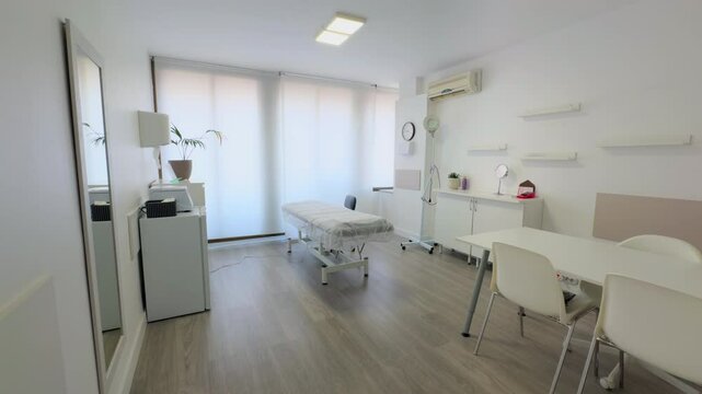 Bright and modern medical or therapy room with a minimalist design. It features a treatment bed, white furniture, and soft lighting, creating a clean and professional atmosphere.