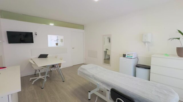 Clean and modern medical or therapy room with a treatment bed, white furniture, and essential equipment. The minimalist design creates a professional and comfortable space.