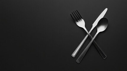 A modern and minimalist composition featuring a high-quality silver fork and spoon crossed over each other on a matte black background, emphasizing their sleek design.