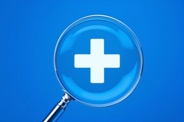 Fototapeta premium Magnifying glass highlighting a medical cross symbol on a blue background. Concept of healthcare, diagnosis, and medical research. Ai generative