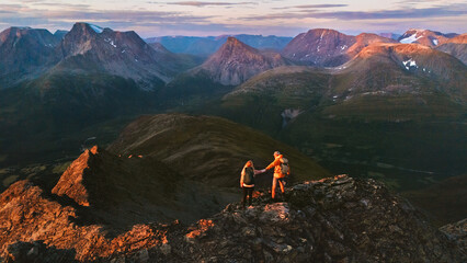 Couple hiking in mountains of Norway aerial view friends adventurers man and woman climbing, active summer vacations healthy lifestyle extreme trip outdoor family trekking in Lyngen Alps