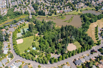 Aerial drone view of Summerlake City Park in Tigard, Oregon, showcasing Stark Reservoir, sports fields, walking trails, lush greenery, picnic areas, and surrounding residential neighborhoods