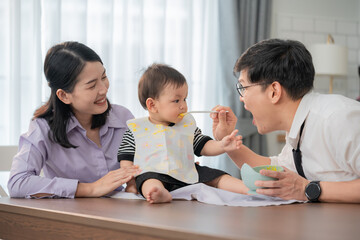 Parents feeding their toddler in a cozy kitchen during mealtime together