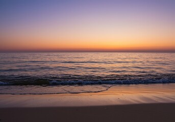 Tranquil beach at sunset with gentle waves and vibrant sky