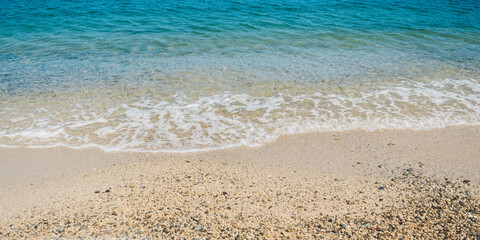 Summer beach sand, blue waves and white foam