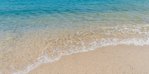 Summer beach sand, blue waves and white foam