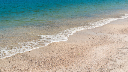 Summer beach sand, blue waves and white foam