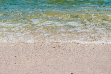 Summer beach sand, blue waves and white foam