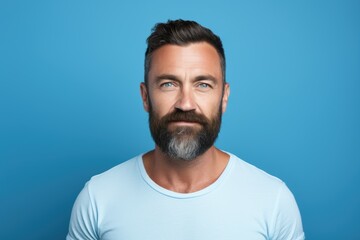 Obraz premium A man with a beard and a blue shirt is smiling