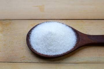 Monosodium glutamate in bowl on wooden background.