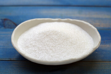 Monosodium glutamate in bowl on wooden background.