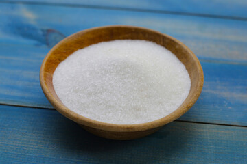 Monosodium glutamate in bowl on wooden background.