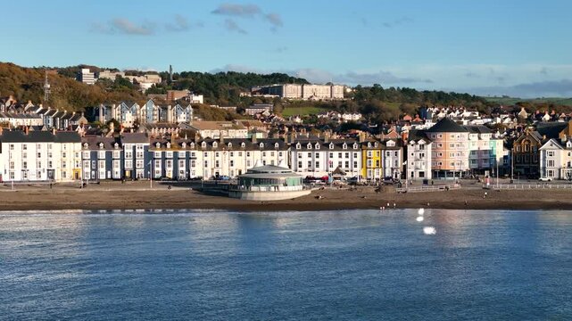 Beautiful drone footage of Aberystwyth town at sunset, showcasing the promenade, bandstand, and stunning coastline in golden hour light on a peaceful evening.