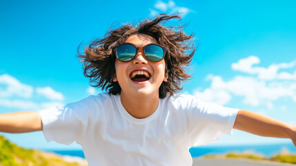 Joyful young woman with sunglasses and casual outfit radiating happiness against a blue summer sky outdoors
