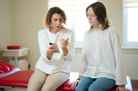 Female doctor consulting patient in treatment office room. Osteopathic medicine and physiotherapy concept. Conversation between two pretty girls. Communication between two women