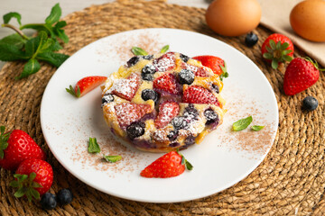Delicious sweet clafoutis tart with blueberries and strawberries baked using a traditional French recipe.