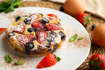 Delicious sweet clafoutis tart with blueberries and strawberries baked using a traditional French recipe.