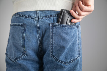 Man putting wallet in his jeans pocket.