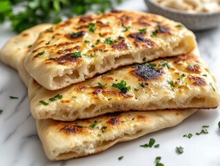 Golden Naan Bread Stacked on Marble Surface with Fresh Parsley Garnish and Creamy Dip in Bowl Overhead Shot
