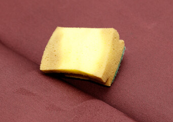 A yellow sponge is sitting on a red cloth