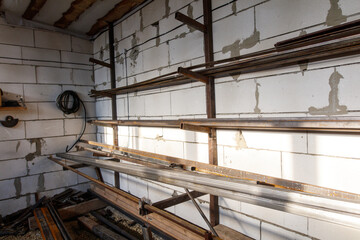 A white wall with metal shelves and a black pipe hanging from the wall