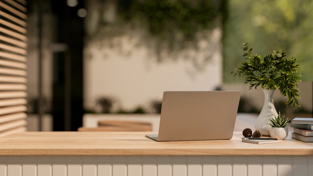 The back view of laptop place on wooden table with decorative items. Workspace with natural light.