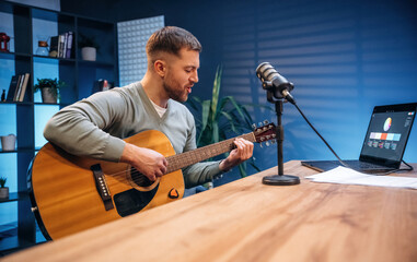 Songwriter with acoustic guitar. Man with microphone in the studio, conception of podcast