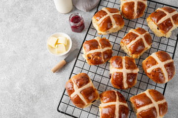 Freshly baked Easter hot cross buns with butter, berry jam and cup of tea on a gray concrete...
