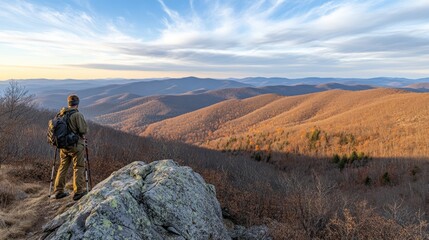 Hiker with backpack gazes at beautiful mountain landscape in autumn