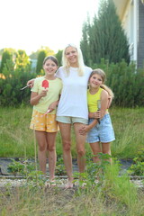 Fototapeta premium a mother walks hand-in-hand with her two children through a lush garden in their backyard.