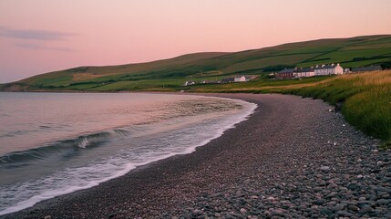 Pebble beach curves along the coast beneath a pink sky
