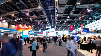 Crowds explore a bustling trade show at a convention center showcasing innovative technologies and services