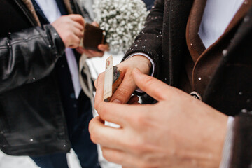 Two people on the street, dressed in warm clothes. One of them is holding a banknote in his hands