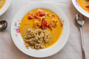 Quinoa porridge with shrimps and tomatoes on dish on table