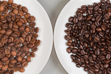 Medium and dark roasted coffee beans on two white plates